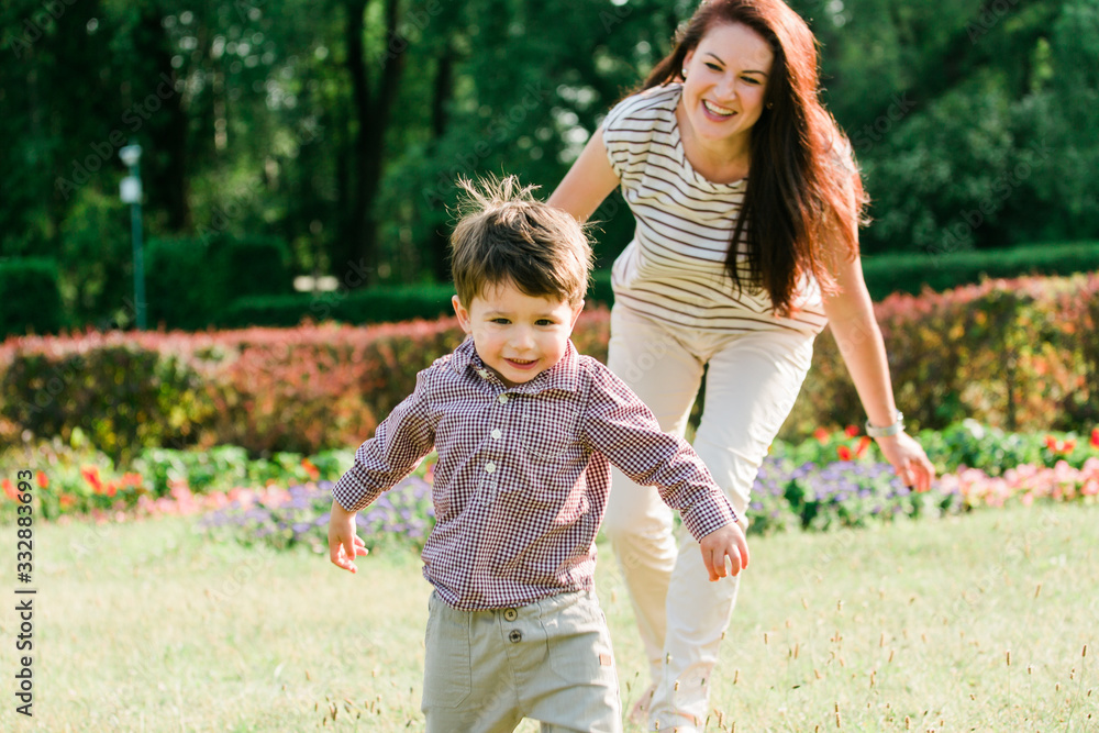 Mother having fun with cute son in summer park. Happy woman with cheerful little boy outdoors Mother having fun with cute son in summer park. Happy woman with cheerful little boy outdoors