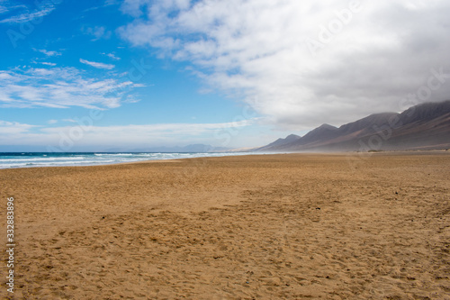 Playa De Cofete Canary Islands, Fuerteventura, Spain. Beach, mountains and Atlantic Ocean against cloudy sky 