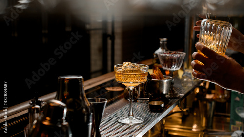 glass of ice brown alcoholic drink stands on bar counter.