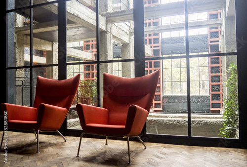 Vintage pair of armchairs standing by big wall of glass.