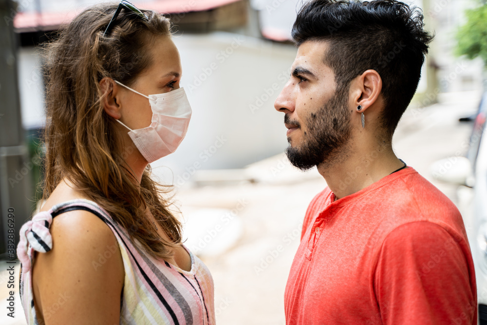 Naklejka premium Young woman with a protective mask facing her couple