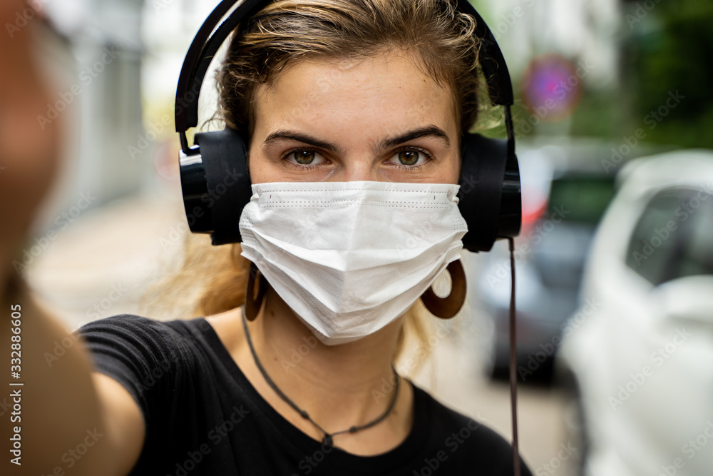 Young girl with a protective mask and headphones to listen to music in the street Young girl with a protective mask and headphones to listen to music in the street