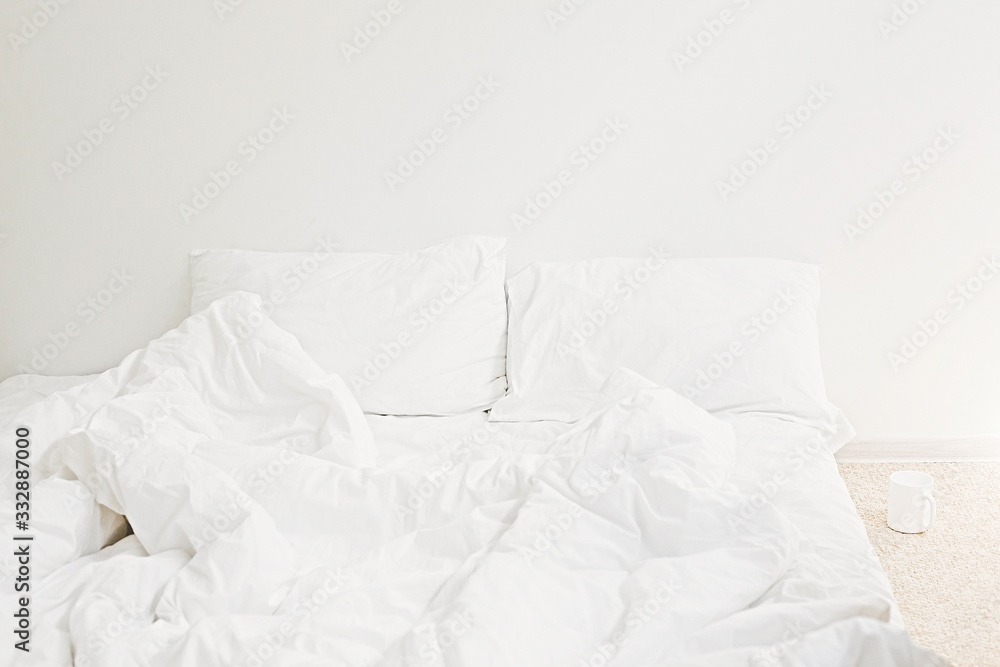 © sonyachny - Cozy white bed in the morning. White sheets and pillow on bed in modern white room. Lazy days. Stay home. Comfortable place. Relax on weekend in hotel room. Messy bed