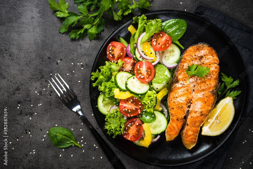 Grilled salmon fish steak with vegetables on black. Grilled salmon fish steak with vegetables on black.