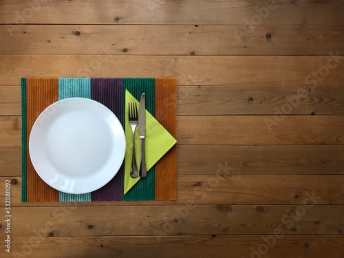 Teller mit Besteck auf Holztisch und grüner Serviette