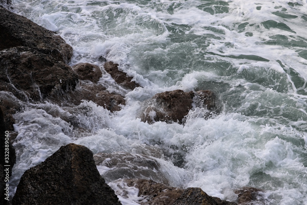 Coastal water breaking over surface of jagged rocks Coastal water breaking over surface of jagged rocks
