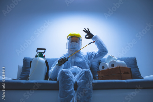 Scientist with protective suit and face mask, bio hazard sprayer for decontamination agaist viruses, germs - toilet paper stock paranoia at home, waiting for end of days. photo