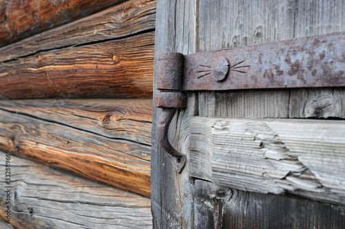 An old door hinge covered with rust on the old wooden gate
