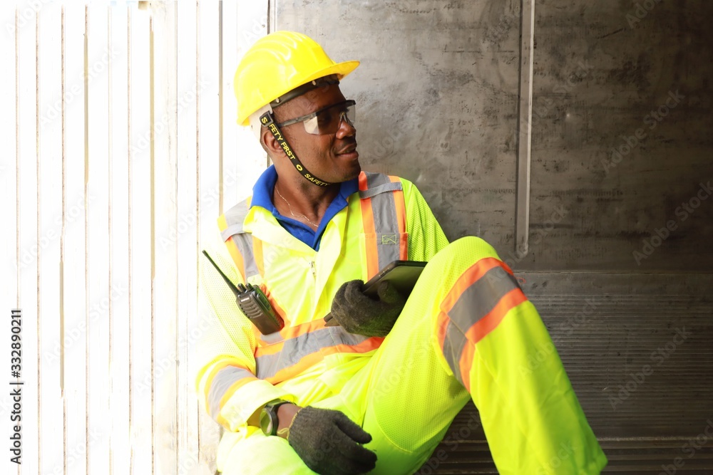 Foreman manual worker at commercial dock, wearing yellow, holding radio communication, for control loading container box from cargo Foreman manual worker at commercial dock, wearing yellow, holding radio communication, for control loading container box from cargo