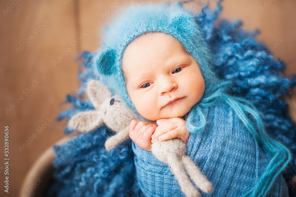 Little newborn baby with a hare closeup and copy space. Newborn photo in a blue diaper Little newborn baby with a hare closeup and copy space. Newborn photo in a blue diaper