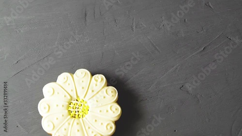 Sweet gingerbread, cookies in the form of flowers and green leaves on a wooden stick on a gray cement background. Sweet pastries, food