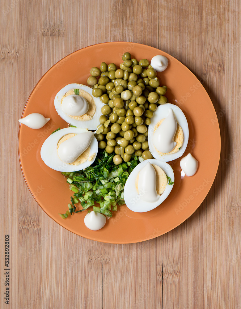 Top view. Boiled eggs with mayonnaise with peas and green onions.
