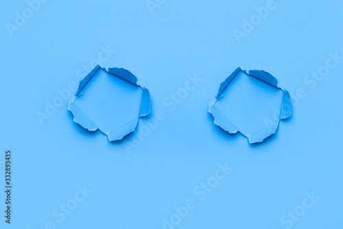 Blue color background with holes in the paper. Copy space.