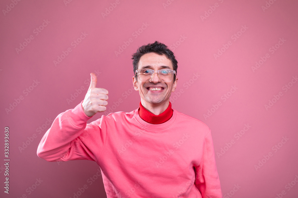 Cheerful young man hold big thumb up and smile. Posing alone on camera. Man isolated over pink background. Cheerful young man hold big thumb up and smile. Posing alone on camera. Man isolated over pink background.
