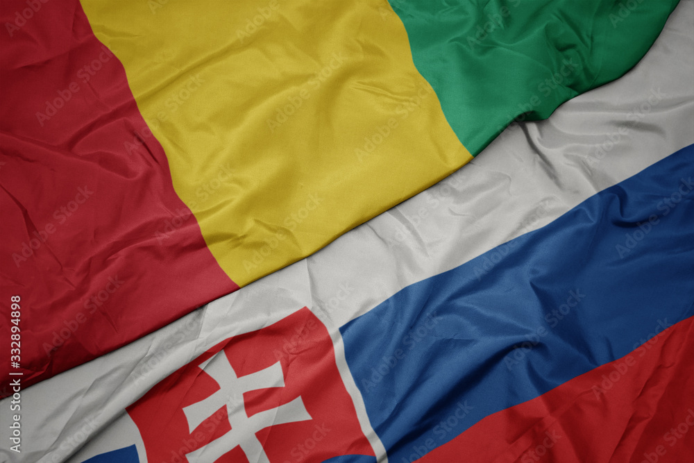 waving colorful flag of slovakia and national flag of guinea.
