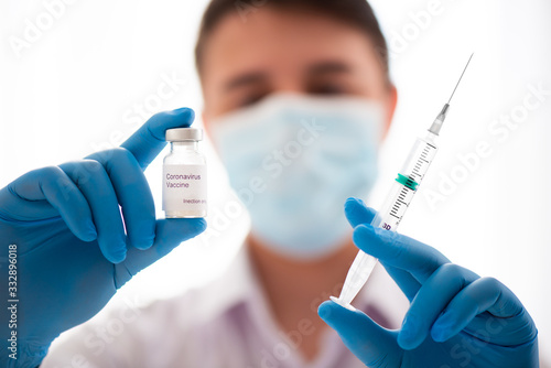 Vaccine bottle and syringe in male hand close up, doctor in medical mask. Concept of vaccination, Covid-19 coronavirus diagnostic, cure for flu virus