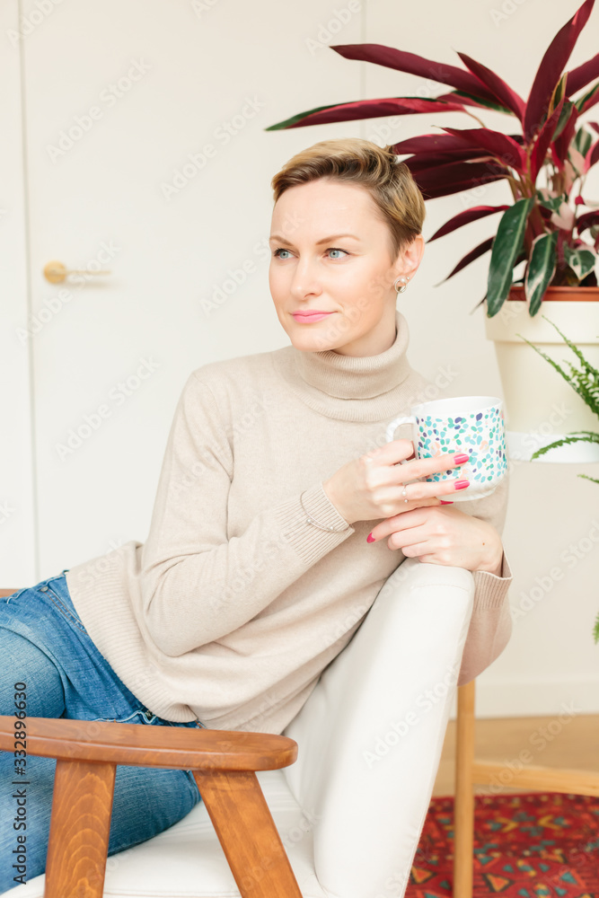 Thoughtful mature woman sitting in cafeteria or at home holding coffee mug while looking away. Middle aged woman drinking tea while thinking. Relaxing and thinking while drinking coffee. Thoughtful mature woman sitting in cafeteria or at home holding coffee mug while looking away. Middle aged woman drinking tea while thinking. Relaxing and thinking while drinking coffee.