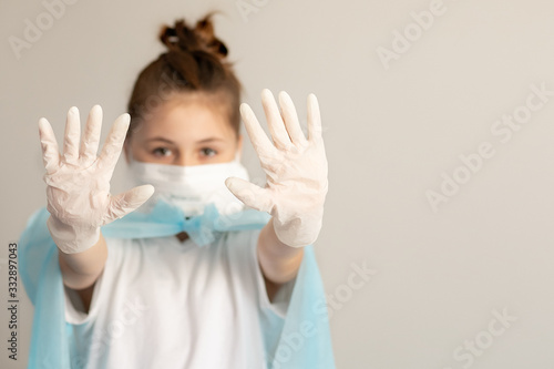 close-up teenager girl in surgical protective mask and rubber gloves on a neutral gray background. virus protection concept © Nataliia