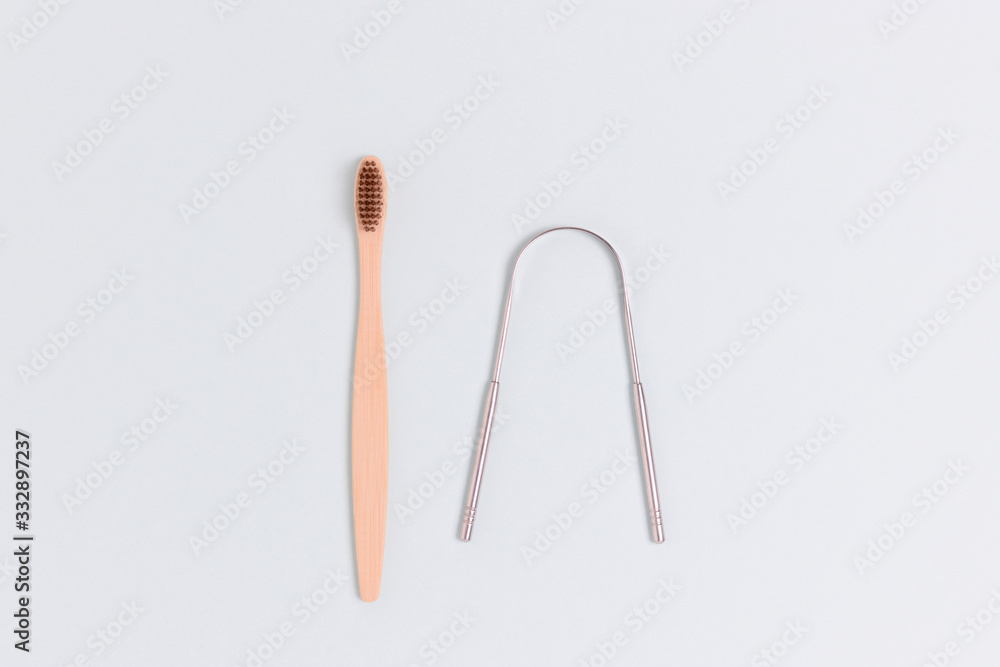 Toothbrush and tongue scraper on a blue pastel background. Zero waste concept. Toothbrush and tongue scraper on a blue pastel background. Zero waste concept.