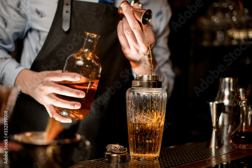 close-up of glassy shaker in which bartender pours drink using beaker.