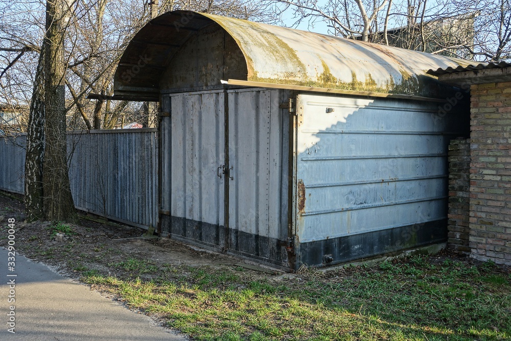 one gray closed metal garage stands outside in green grass one gray closed metal garage stands outside in green grass