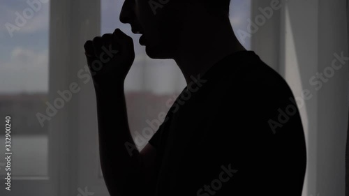 Silhouette of a coughing man on a window background. The patient is treated at home for the virus Covid-19