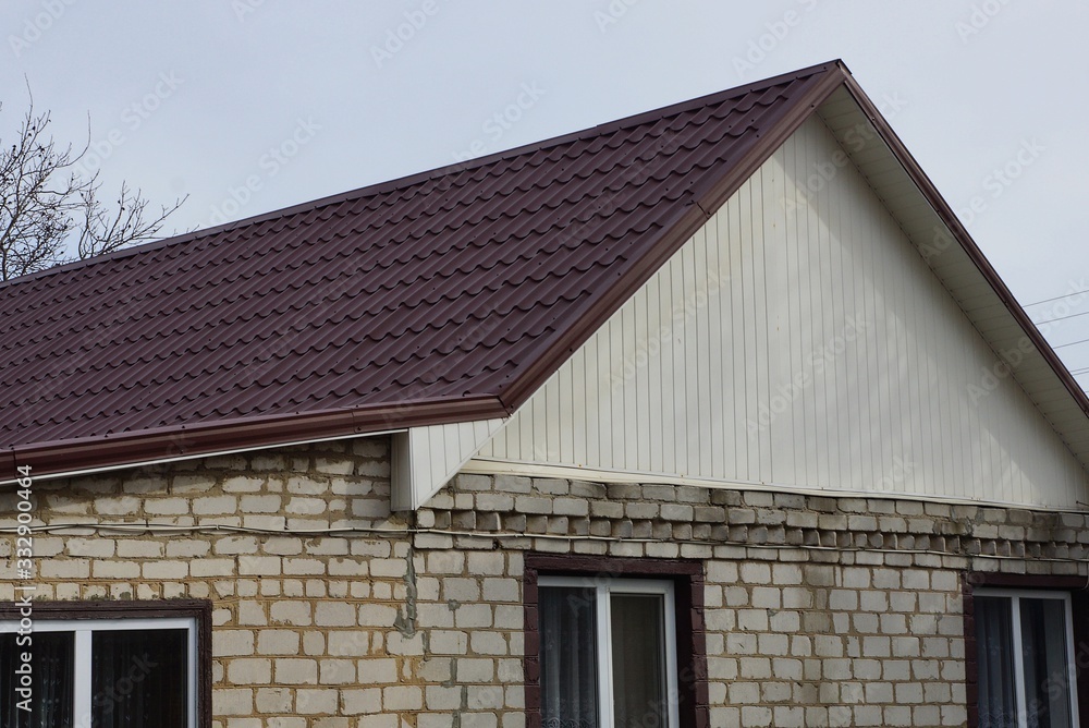 white private brick house with a brown tiled roof against a gray sky