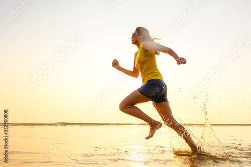 Woman running on beach at sunrise.