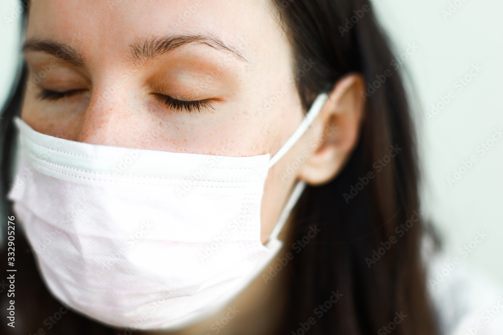 brunette woman with loose hair wearing medical mask with her eyes closed brunette woman with loose hair wearing medical mask with her eyes closed