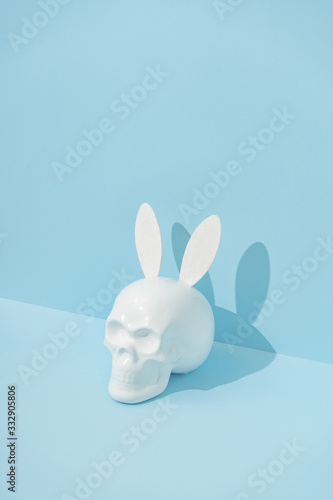 Fototapeta Naklejka Na Ścianę i Meble -  Skull with rabbit or bunny ears on pastel blue background. Creative minimal Easter concept. Hipster idea.