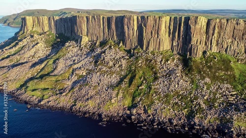 Fair Head or Benmore big cliff and headland near Ballycastle. Atlantic coast, County Antrim, Northern Ireland, UK. Famous climbing place. Aerial 4K flyby video in sunset light