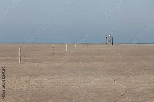 Orientation sticks for fog to find the escape tower. In the foreground there is mud at low tide in the Wadden Sea and in the background the North Sea.