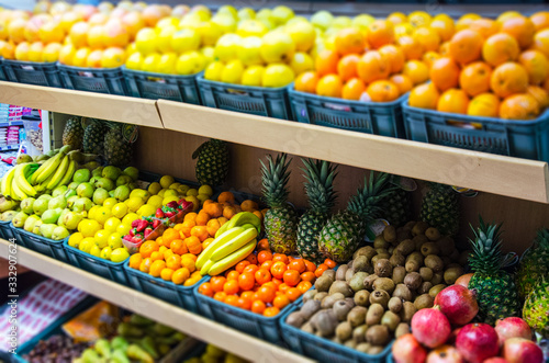 Fruit on a shelf in the market. Bananas, oranges, lemons, strawberries, apples, pineapples, kiwi are presented. © Alexander