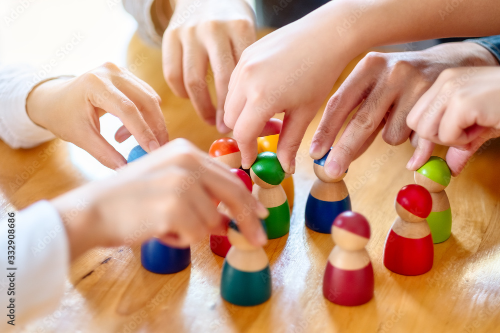 People choosing and picking up wooden figure from a group on the table People choosing and picking up wooden figure from a group on the table