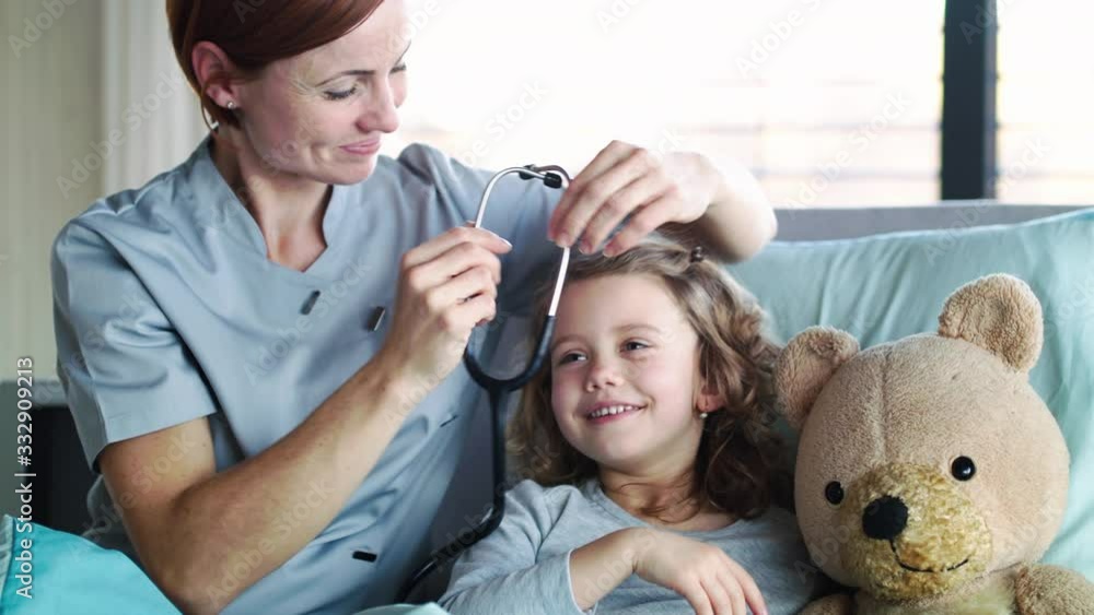 Friendly woman doctor examining small girl in bed in hospital. Friendly woman doctor examining small girl in bed in hospital.