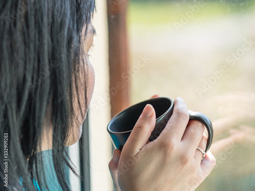 Femme triste avec un café devant sa fenêtre