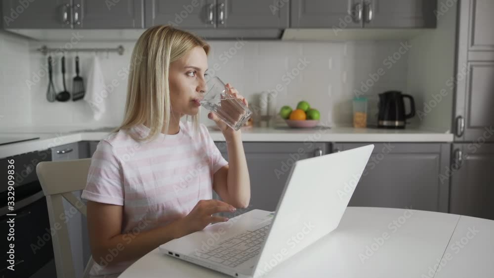 Young woman using laptop computer and phone at kitchen. Business woman working on notebook Young woman using laptop computer and phone at kitchen. Business woman working on notebook