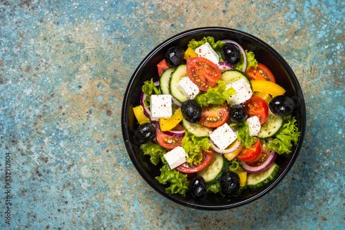 Greek salad in black plate on the table.