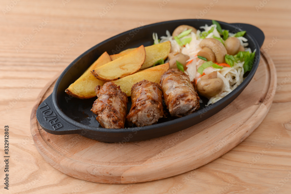 Grilled meat in mushroom's sauce and baked potato with cabbage mushroom salad in a pan on rustic wooden table. Grilled meat in mushroom's sauce and baked potato with cabbage mushroom salad in a pan on rustic wooden table.