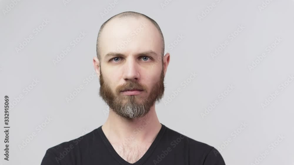 Strict bearded man looking at a camera over white background. Serious dissatisfied man. Concept of emotions. Strict bearded man looking at a camera over white background. Serious dissatisfied man. Concept of emotions.