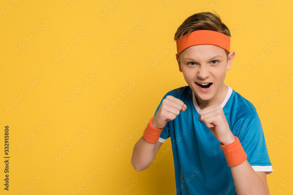 aggressive kid showing fists and screaming on yellow background aggressive kid showing fists and screaming on yellow background
