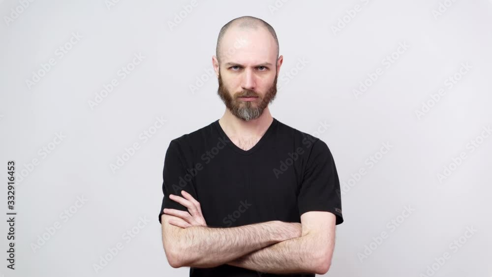 Strict bearded man looking at a camera over white background. Serious dissatisfied man keeps hands crossed. Concept of emotions. Strict bearded man looking at a camera over white background. Serious dissatisfied man keeps hands crossed. Concept of emotions.