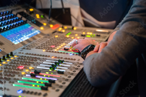 Working sound engineer hand on a audio mixer panel during broadcasting concert