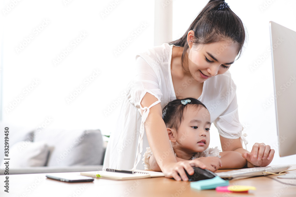 Asian mother watching her daughter who is learning to use the computer. Mom and kids, education, family relationship, child care, technology for children concept. Asian mother watching her daughter who is learning to use the computer. Mom and kids, education, family relationship, child care, technology for children concept.
