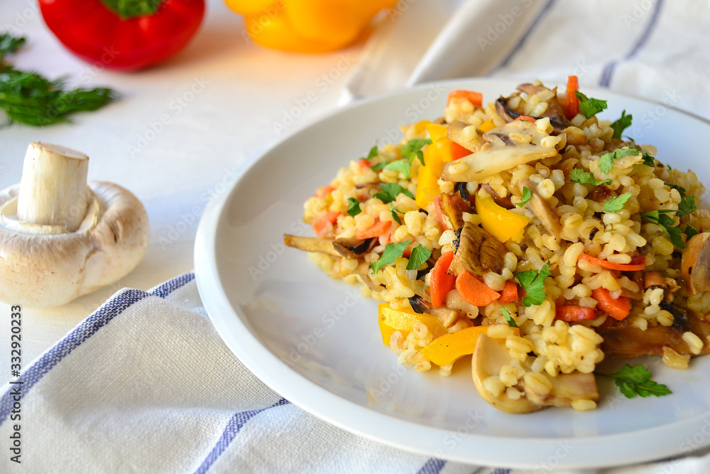 Bulgur with vegetables on a white plate on a kitchen table. Bulgur with vegetables on a white plate on a kitchen table.