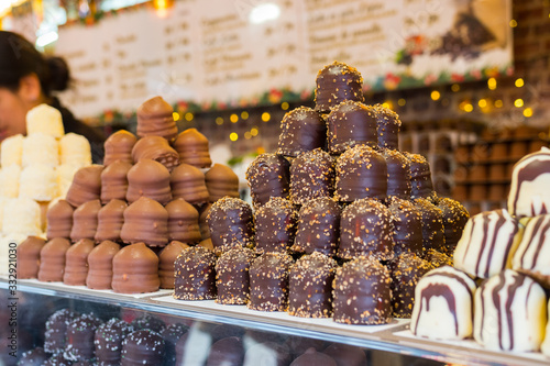 Dark Chocolate covered marshmallows. Beautiful big pile of delicious pastries. Christmas market food stand, Paris, France. Blurred background.
