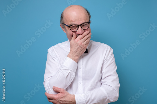 Senior man laughing and embarrassed giggle covering mouth with hands photo
