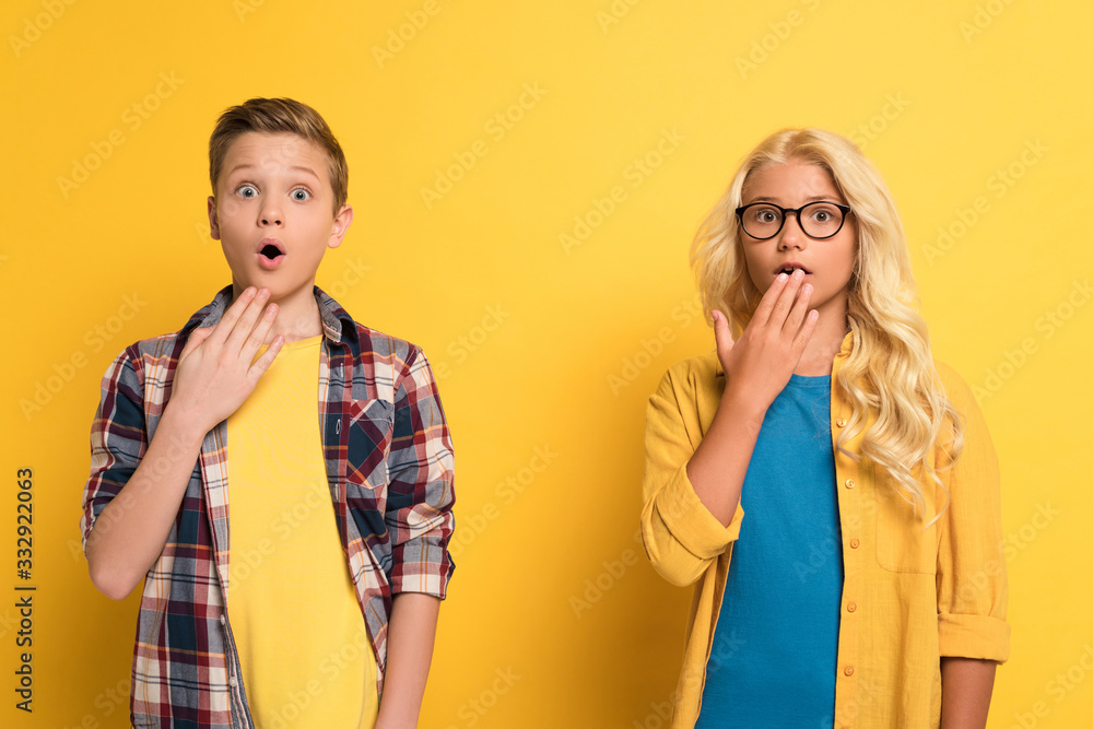 shocked and cute kids looking at camera on yellow background shocked and cute kids looking at camera on yellow background