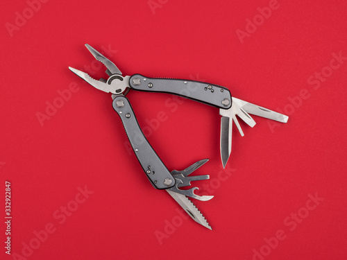 Multitool on a red background closeup.