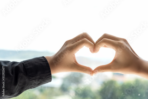 Two hand touch together in a heart shape on nature background.